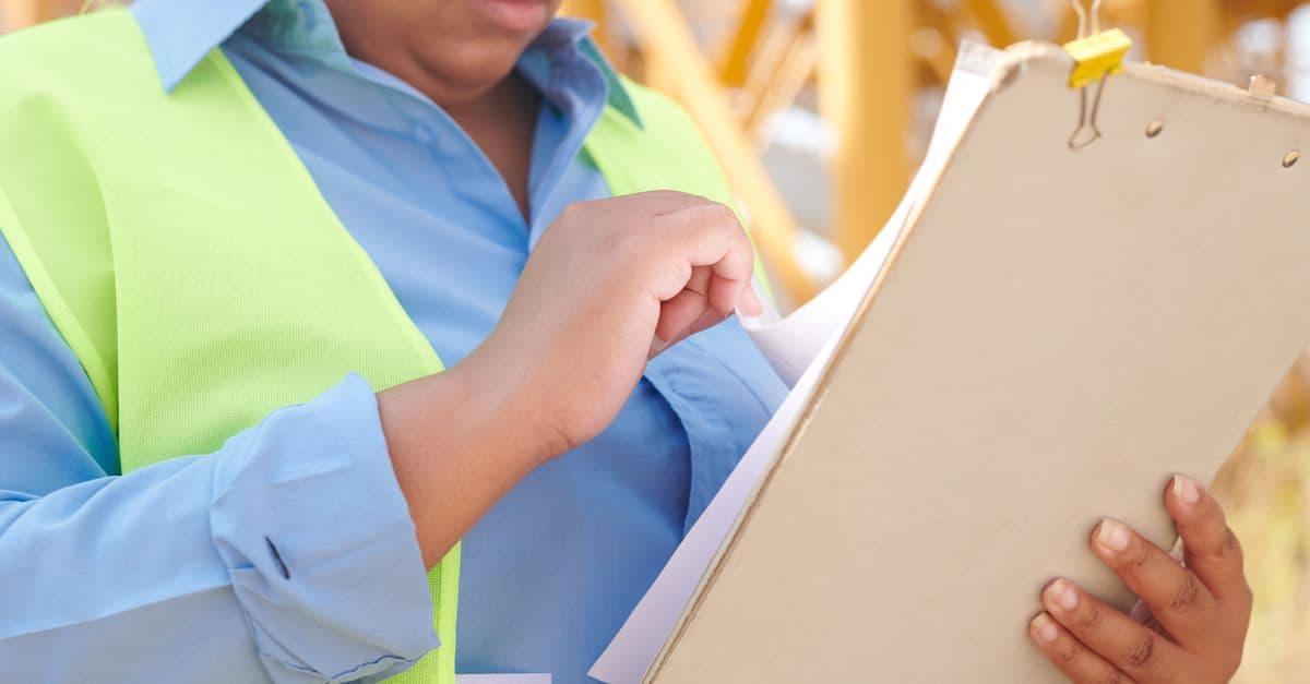Ouvrier consultant un document de sécurité sur un chantier de bâtiment